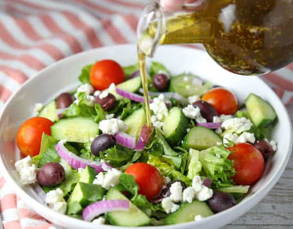 Homemade Greek Salad Dressing being poured on the salad
